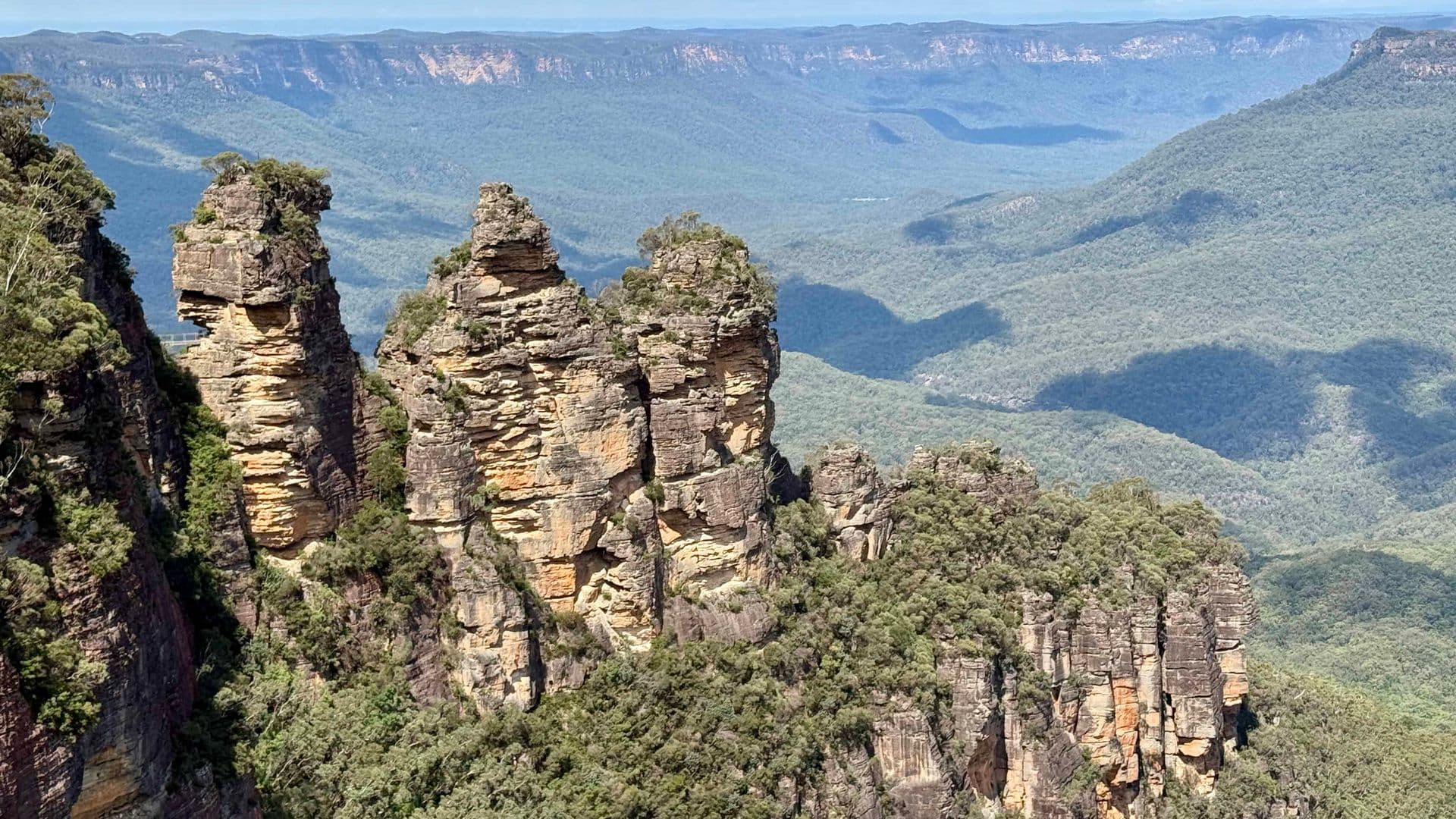 Three Sisters rock formation at Echo Point with cloud shadows dappling the green Jamison Valley, Blue Mountains NSW.