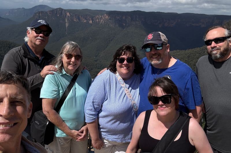 Family group with tour guide at Govett's Leap lookout, Blue Mountains, with dramatic valley views behind them.
