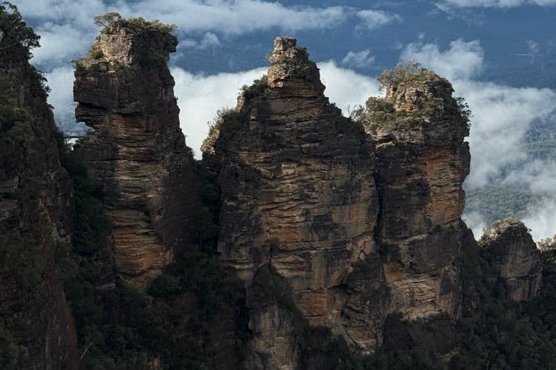 Three Sisters rock formation at Echo Point, Blue Mountains, surrounded by low autumn clouds filling the Jamison Valley below