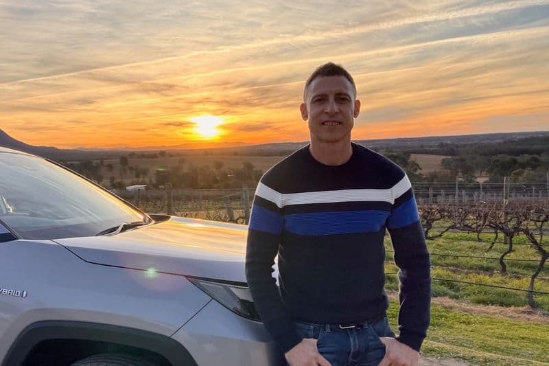 Tour guide Todd Craft standing beside his private tour vehicle at golden-hour sunset in Hunter Valley wine country, NSW.