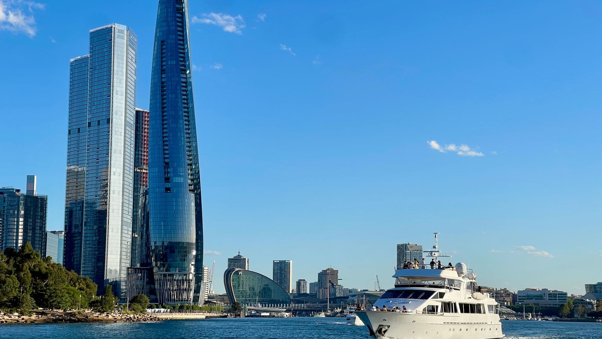Sydney CBD skyline viewed from the harbour, luxury yacht in foreground, Crown Sydney tower and Barangaroo waterfront prominent