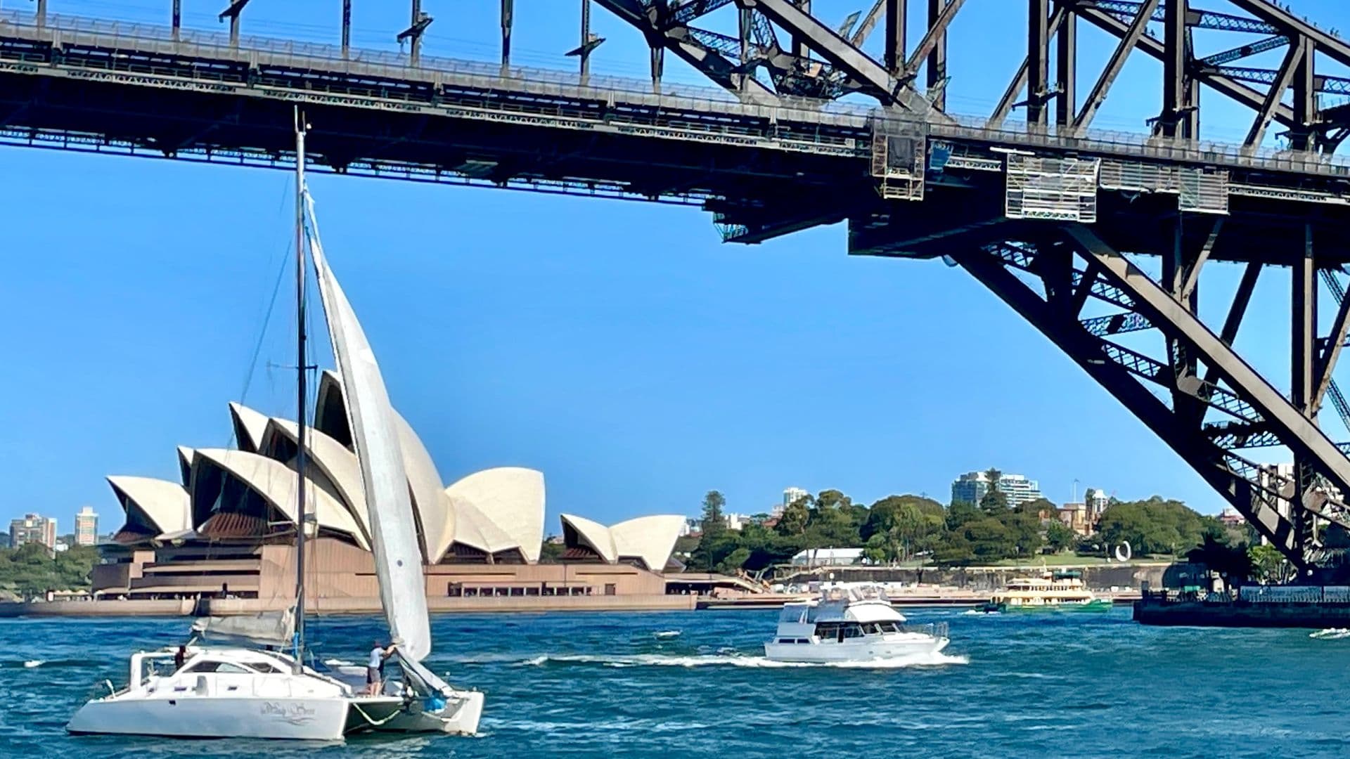 Sydney Opera House and Harbour Bridge framing two boats on the harbour, captured on a clear day